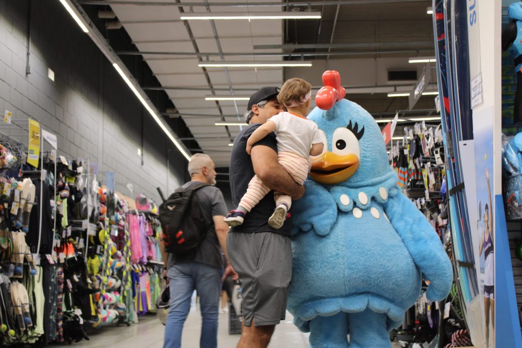 Adulto com criança ao lado da personagem Galinha Pintadinha na Decathlon