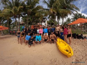 Grupo reunido na praia com caiaque amarelo durante atividade do Clube da Aventura