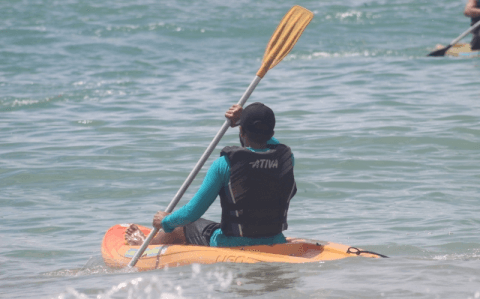 Pessoa remando em caiaque laranja no mar