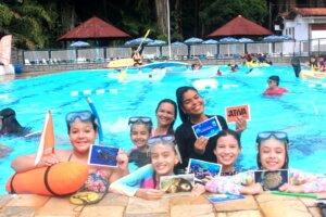 Crianças reunidas na piscina durante atividade de colônia de férias