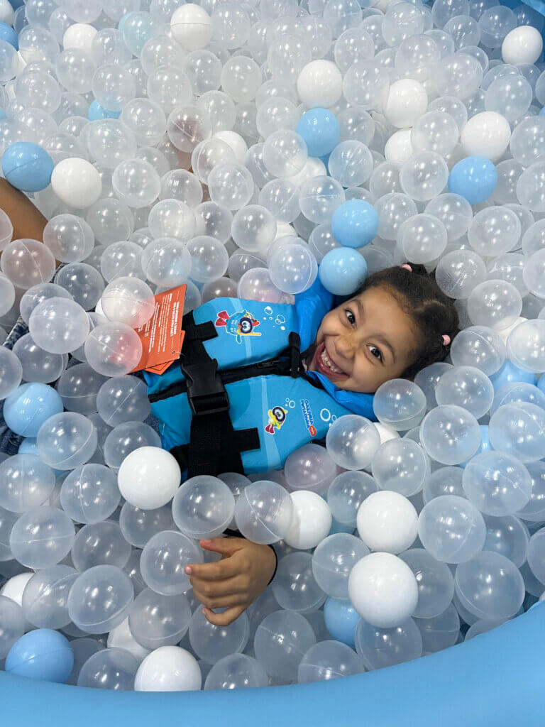 Criança usando colete infantil em piscina de bolinhas