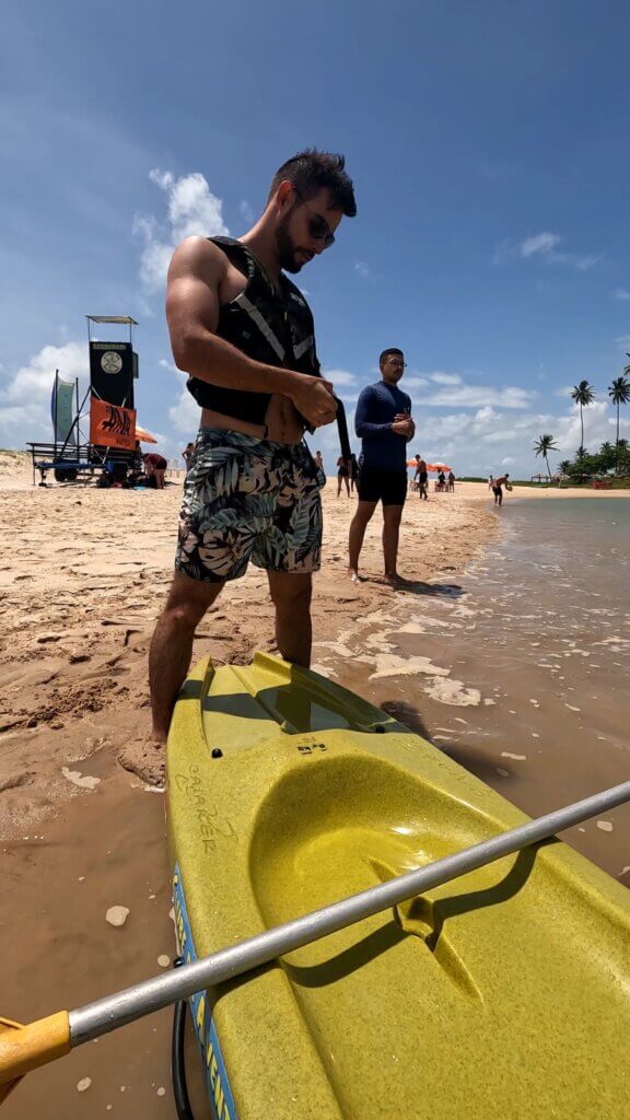 Participante preparando caiaque amarelo na praia durante capacitação de condutores