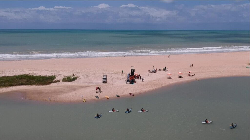 Vista aérea de participantes em caiaques entre o rio e o mar