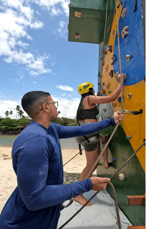 Participante em atividade de escalada com acompanhamento na praia