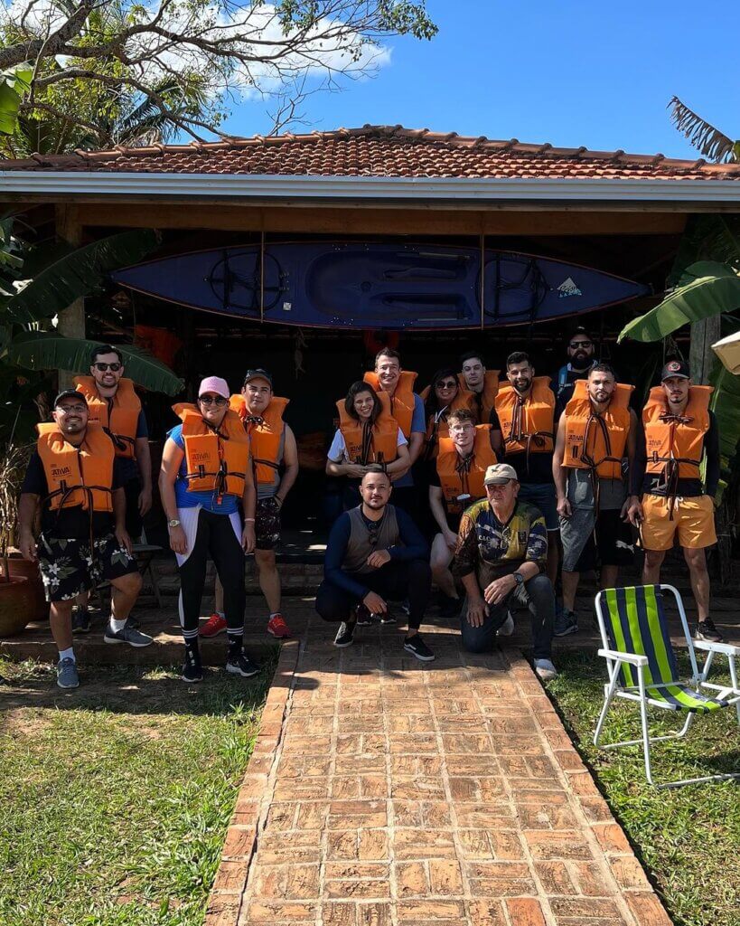 Grupo reunido usando coletes salva-vidas laranja após atividade aquática