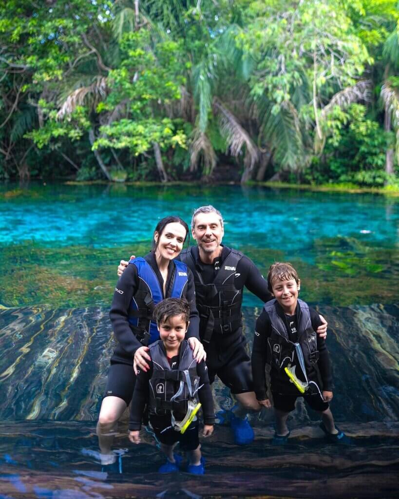 Família usando coletes salva-vidas durante atividade em água natural