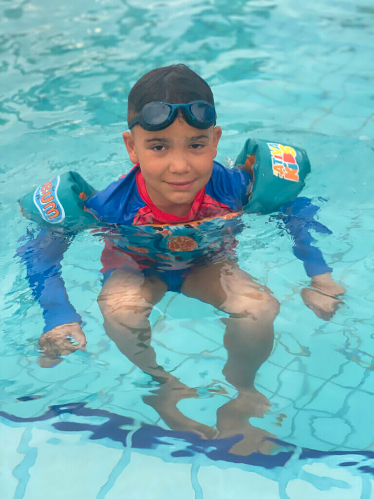 Criança na piscina usando colete salva-vidas infantil colorido