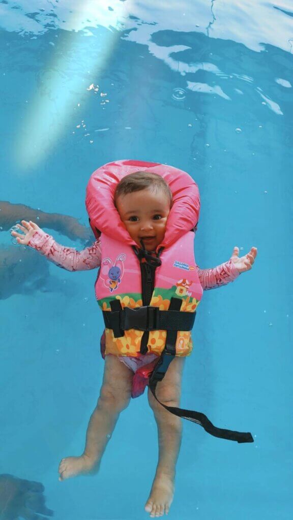 Criança submersa na piscina usando colete salva-vidas infantil