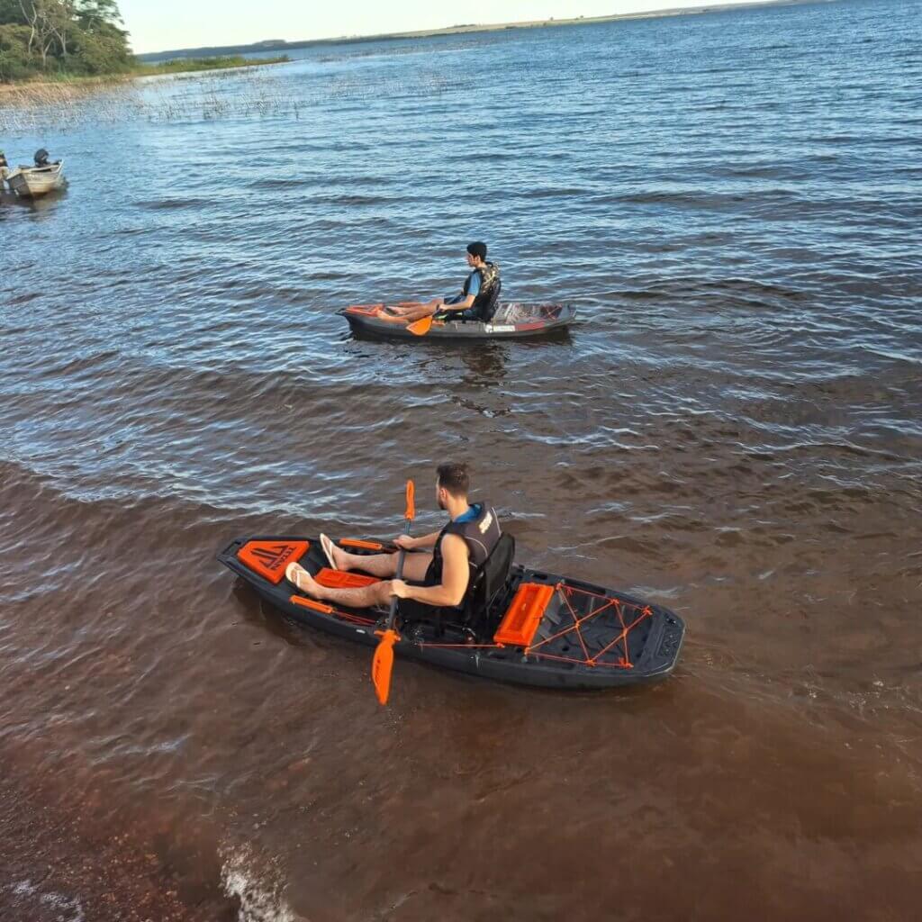 Pessoas em caiaques usando coletes salva-vidas em área de água aberta