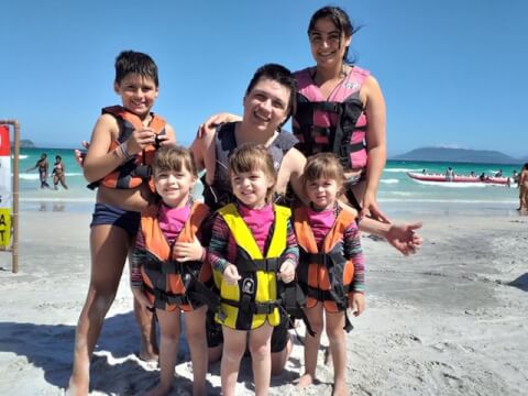 Grupo de adultos e crianças na praia usando coletes salva-vidas