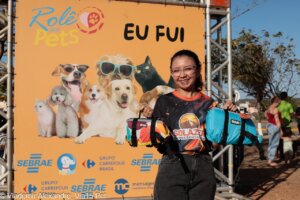 Participante do Rolê dos Pets segurando produtos Ativa Pet diante do painel do evento