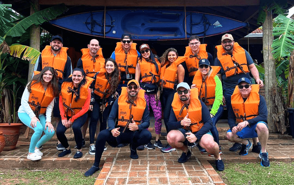 Grupo usando coletes salva-vidas laranja durante atividade na praia