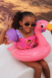 Criança usando colete infantil rosa sentada em boia de flamingo