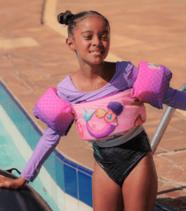 Criança usando colete infantil rosa da coleção Pequenos Universos à beira da piscina