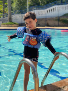 Criança usando colete infantil azul da coleção Pequenos Universos ao lado da piscina