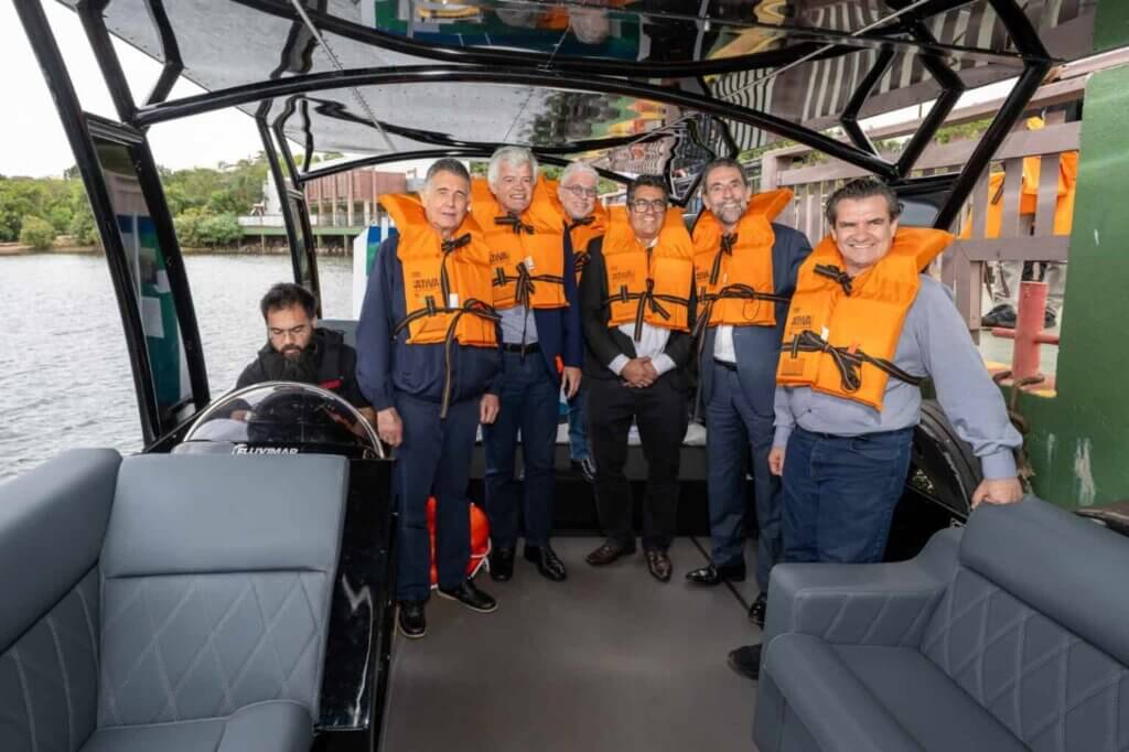 Grupo usando coletes salva-vidas laranja a bordo do barco de hidrogênio JAC H1
