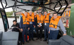 Grupo usando coletes salva-vidas laranja a bordo do barco de hidrogênio JAC H1