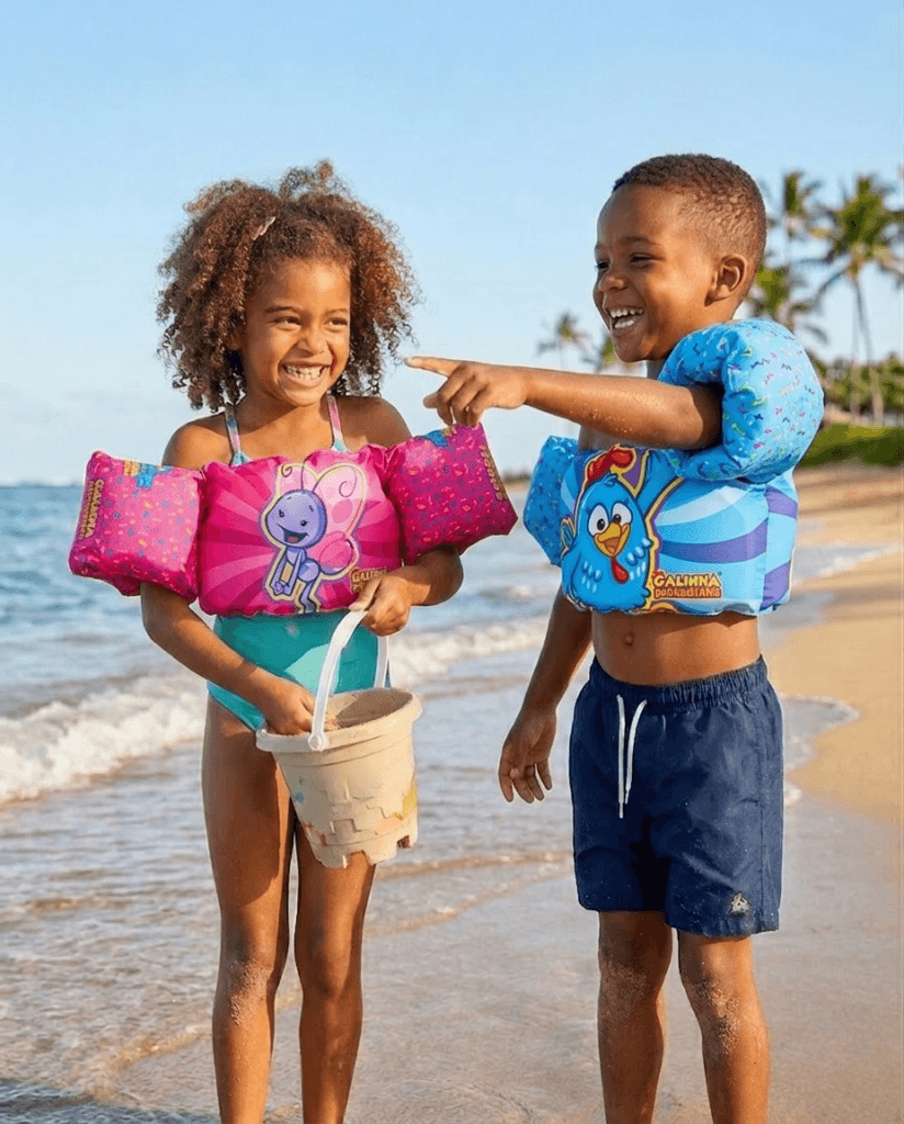 Duas crianças brincando na praia com dispositivos de flutuação infantis coloridos