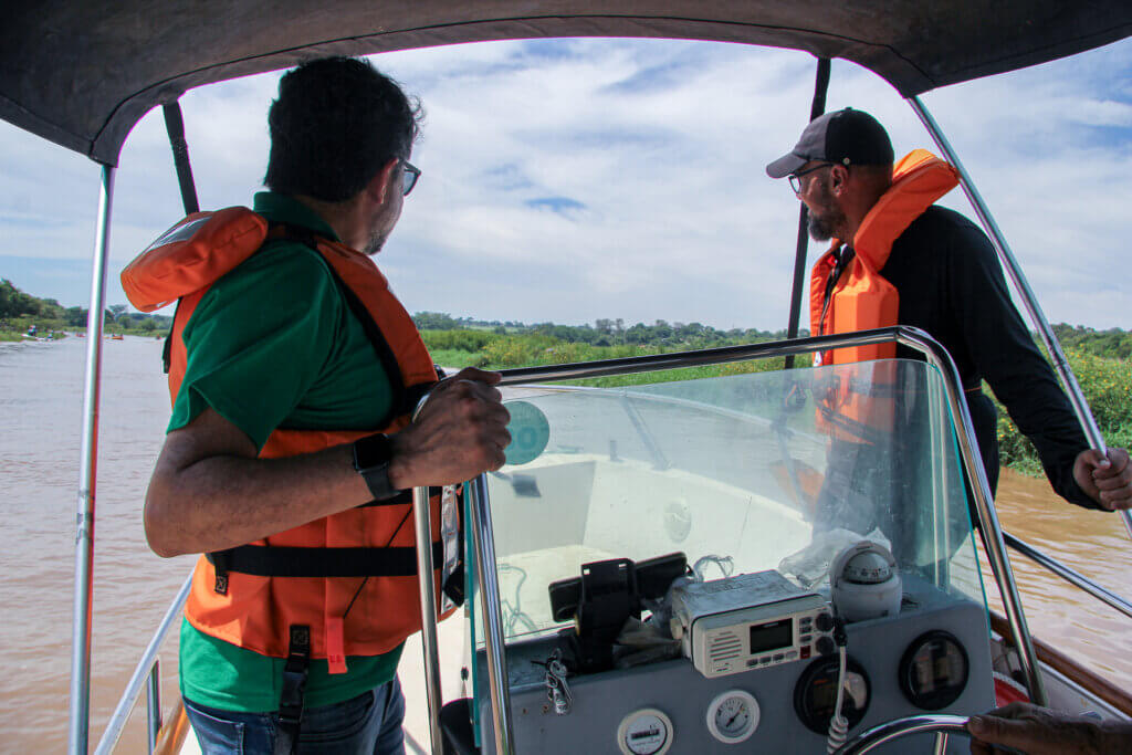 Dois participantes usando coletes salva-vidas a bordo de embarcação no Rio Atibaia