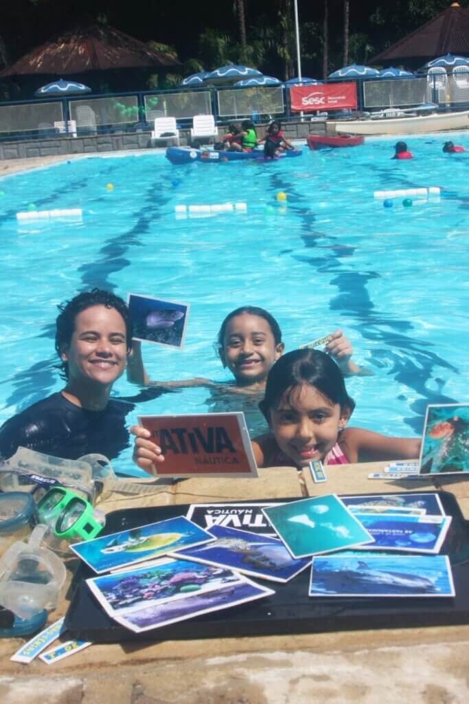 Grupo na piscina exibindo materiais educativos da Ativa Náutica